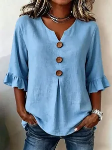 Detail view of blue V-neck linen blouse featuring large buttons and ruffle sleeves
