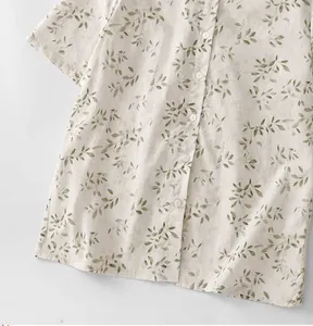 Detail view of a loose summer blouse featuring a delicate green leaf print and buttons.