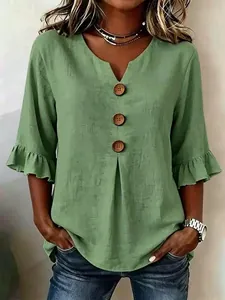 Close-up detail of green V-neck cotton linen top with large buttons and ruffle sleeves