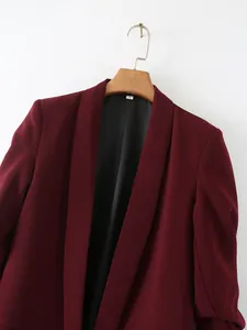 Primer plano de un blazer color burdeos con mangas fruncidas en percha de madera