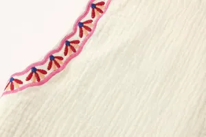 Primer plano de los detalles del bordado floral de colores en un chaleco blanco casual.