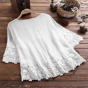 Gedetailleerde weergave van witte katoenen linnen blouse met kanten rand aan zoom en mouwen