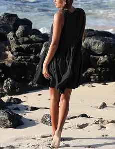 Back view of a chic black V-neck sleeveless pleated mini dress on a sunny beach