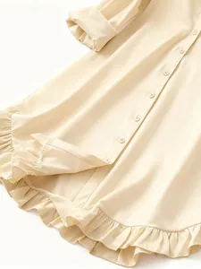 Close-up view of elegant cream woman shirt featuring ruffled hem and textured fabric buttons