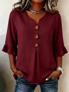 Close-up of burgundy V-neck blouse with ruffle sleeves and wooden button details