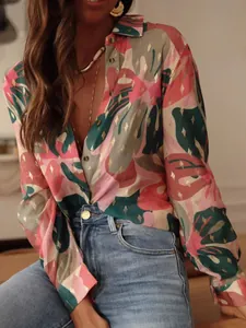 Detail of tropical leaf print long sleeve shirt with elegant lapel and gold accents.