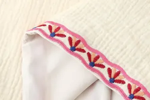 Primer plano detallado de bordado floral en un chaleco de moda blanco texturizado