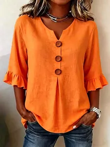 Detailed view of orange V-neck cotton linen blouse with ruffle sleeves and large buttons
