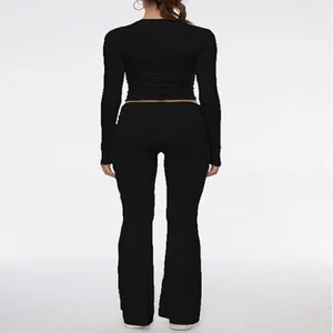 Full back view of black long sleeve crop top and low waist flared yoga pants set