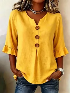Detail of yellow cotton linen V-neck blouse with large buttons and ruffle sleeves