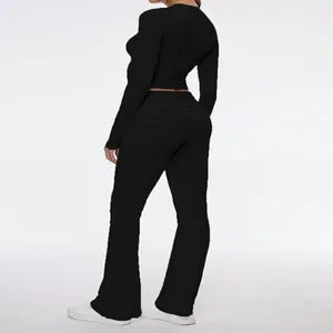 Rear view of black long-sleeve crop top and flare pants set on model in studio