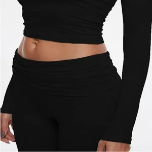 Detail view of black long-sleeve crop top and low-rise pants with ribbed texture.