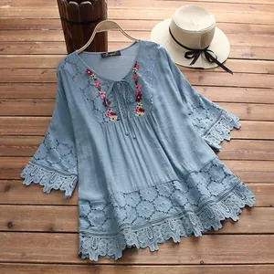 Detail van blauwe katoen linnen blouse met geborduurde bloemen en kanten details