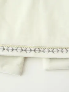 Primo piano dettagliato di paillettes dorate ed eleganti ricami su morbido velluto bianco