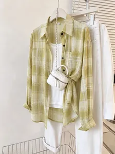 Detail view of a yellow plaid chiffon shirt styled with white tank top and pants