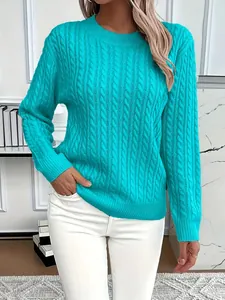 Close-up of a stylish teal cable knit crew neck sweater on a model with white jeans