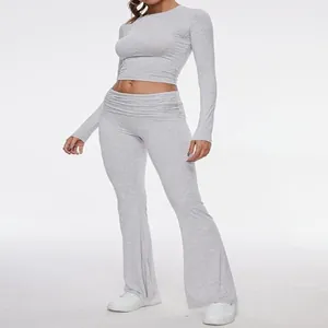 Full view of grey two-piece workout set with long-sleeve crop top and flare pants