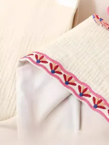 Detalle de primer plano de un chaleco bordado blanco que muestra la textura de la tela