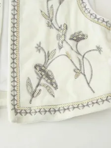 Dettaglio ravvicinato di un gilet in velluto bianco con ricami floreali e paillettes luccicanti