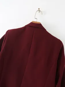 Vista posterior detallada de una chaqueta de traje burdeos entallada para mujer en percha.