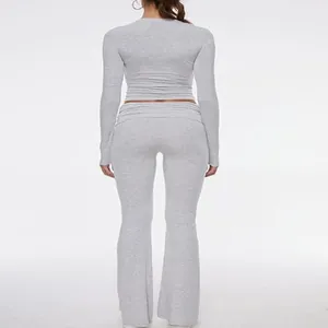 Back view of grey tight-fitting long sleeve crop top and low waist flare pants set.