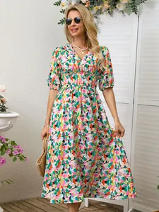 Full-length view of a woman wearing a vibrant floral print maxi dress in a garden setting