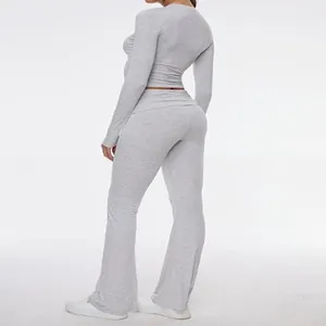 Side view of woman in grey long sleeve crop top and flared yoga leggings activewear set