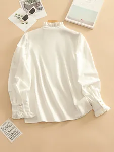 A detailed view of an elegant white ruffle neck blouse with pearl button cuffs