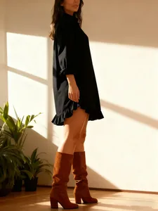 Side profile of a woman wearing an elegant black long-sleeve shirt with a ruffled hem