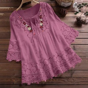 Detail van bloemig borduurwerk en kanten rand op een paars-roze katoenen boho-blouse