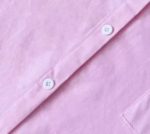 Dettaglio macro di camicia in lino rosa con trama del tessuto e bottoni bianchi