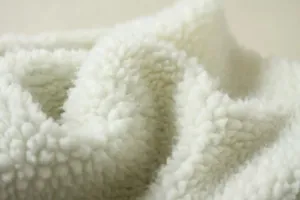 Detailed macro view showing the soft white sherpa fleece lining of a winter denim coat