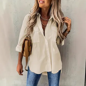 Detail van een minimalistische beige loszittende blouse met lange mouwen en borstzakken