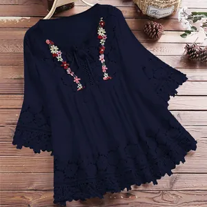 Detail van marineblauwe katoenen linnen blouse met bloemenborduursel en kanten afwerking