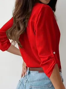 Detail view of a vibrant red long-sleeved shirt featuring a chic metal button on the cuff