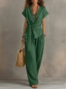 Model wearing elegant green V-neck tie-waist top and matching wide-leg trousers set