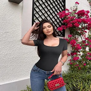 Dettaglio del body nero a costine con scollo quadrato abbinato a jeans blu e borsa rossa