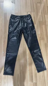 Vista frontale dei pantaloni da uomo in pelle PU nera slim fit distesi sul pavimento