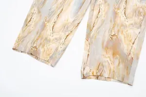 Vue détaillée de l'imprimé tie-dye marbré et de la texture satinée du pantalon droit