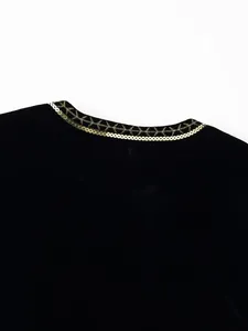 Dettaglio ricamo di paillettes dorate su un lussuoso gilet di velluto nero.