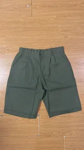 Detailed front view of olive green men's breathable linen shorts flat lay on wooden floor