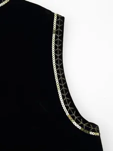 Dettaglio di gilet in velluto nero con finiture in paillettes dorate e ricami.
