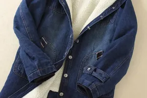 Detailed macro view of the thick white sherpa lining and blue denim fabric of a winter coat