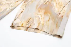 Gros plan de l'ourlet d'un pantalon en satin imprimé marbre montrant la texture