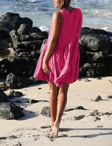 Close-up rear view of a vibrant hot pink sleeveless pleated mini dress on a sunny beach