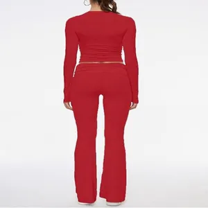 Back view of red two-piece tight set featuring a long sleeve crop top and flared pants