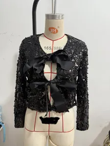 Detailed view of black sequined cropped jacket with double front ribbon bow ties.