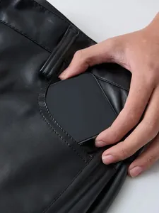 Vista dettagliata della tasca anteriore funzionale di pantaloni in ecopelle nera da uomo