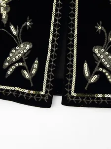 Primo piano dettagliato del ricamo floreale in paillettes dorate su gilet in velluto nero
