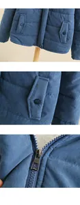 Detail view of the durable zipper and snap pocket on this blue quilted winter jacket.